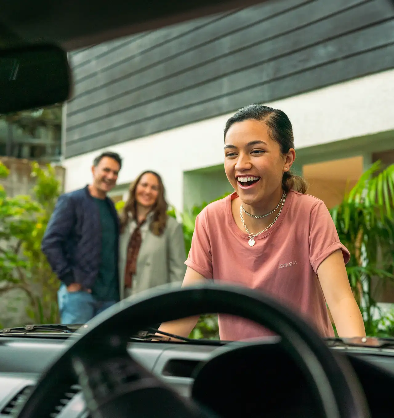 A girl excited about her first car, a gift from her parents