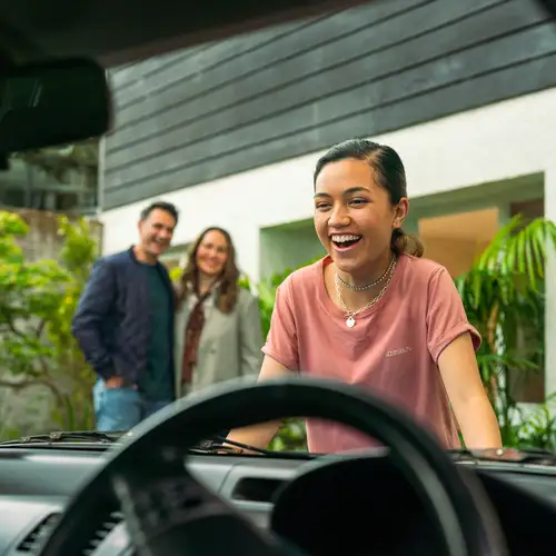 A girl excited about her first car, a gift from her parents