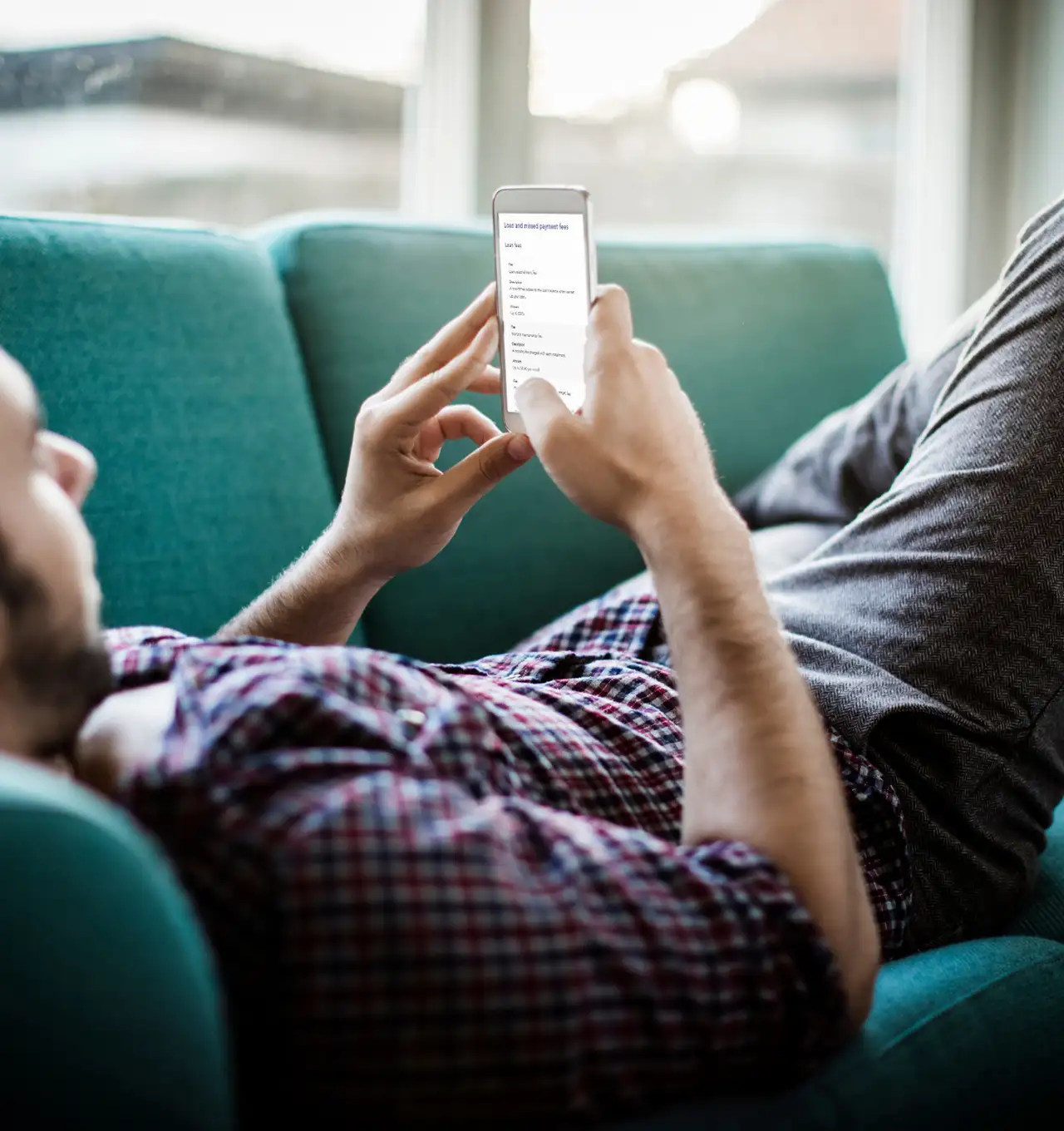 Man relaxing on couch while looking at our website on his phone