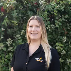 Woman standing in front of hedge posing for headshot