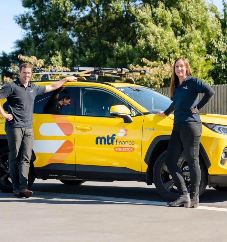 Dan and Amanda from MTF Finance Rolleston standing beside a branded vehicle