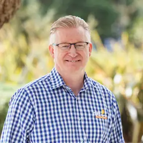 Man posing for headshot with tussock in foreground