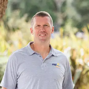 Man posing for headshot with tussock in foreground