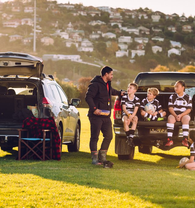 Man talking to kids in the back of a ute at a rugby game