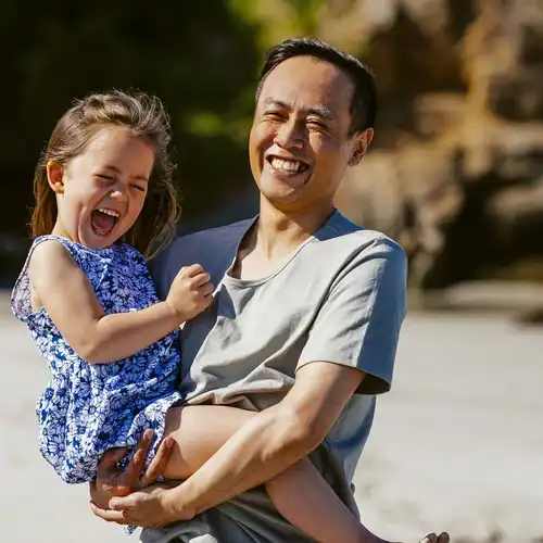 A father holding his daughter while at the beach
