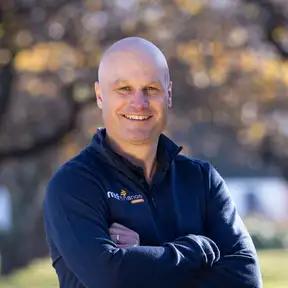 Man posing for a photo with trees and grass in foreground