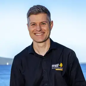 Man standing on beach posing for headshot with Rangitoto in foreground