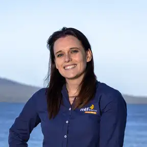 Woman standing on beach posing for a headshot with Rangitoto in the foreground