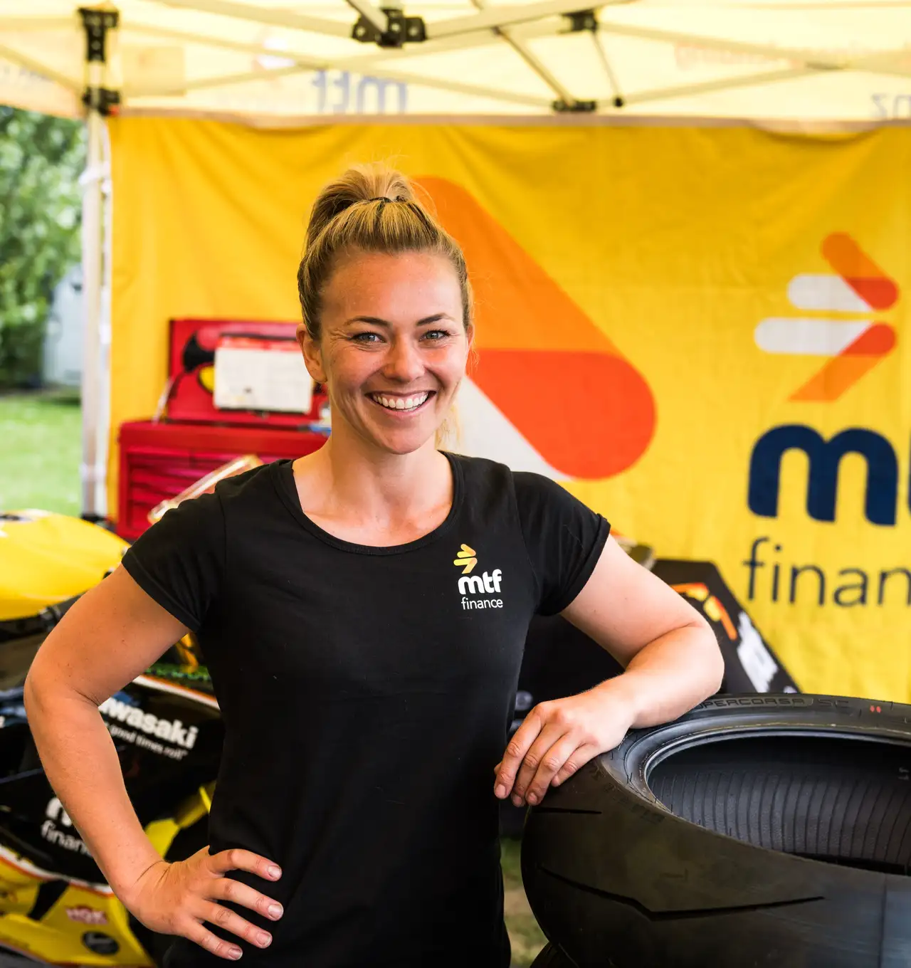 Avalon Biddle alongside her racing motorcycle in a tent