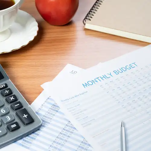A desk showing a calculator and written monthly budget